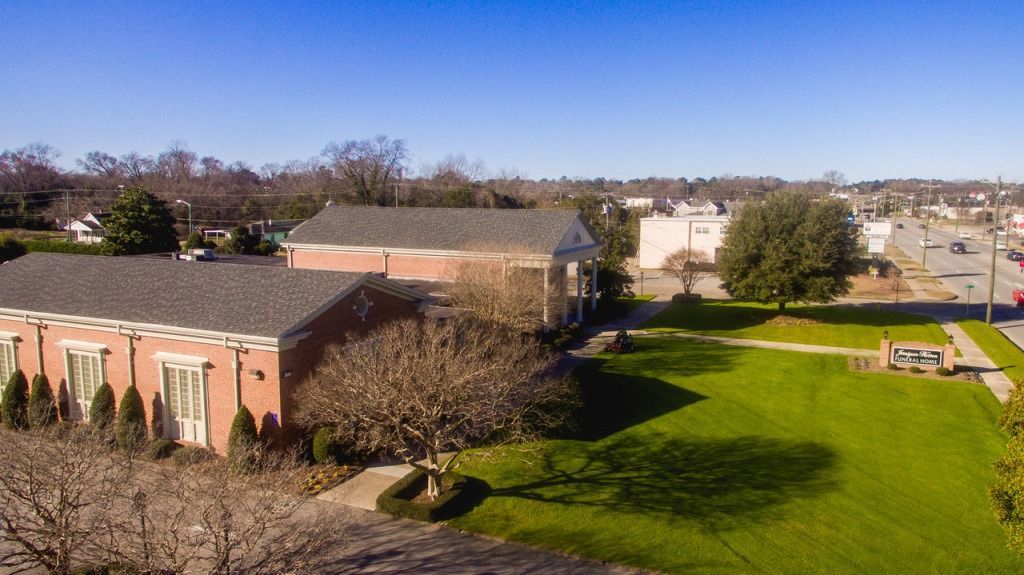 Brick building with a green lawn, bare tree, and blue sky.