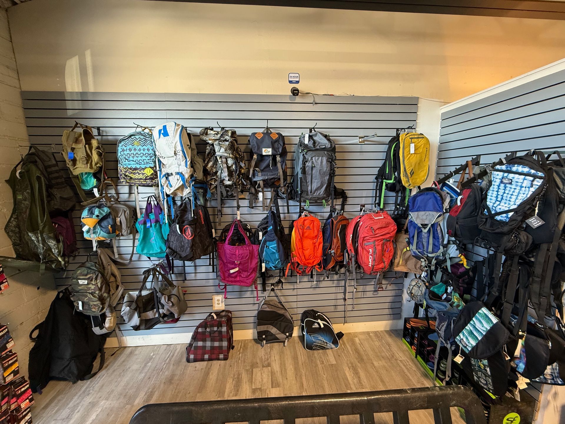 A room filled with lots of backpacks hanging on a wall.