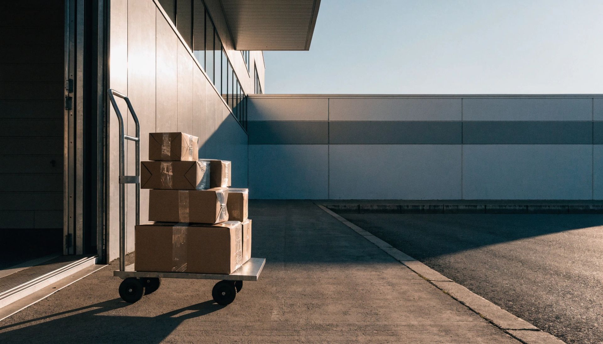 Boxes stacked on a cart outside a warehouse dock for commercial loading services Boxes stacked on a cart outside a warehouse dock for commercial loading services