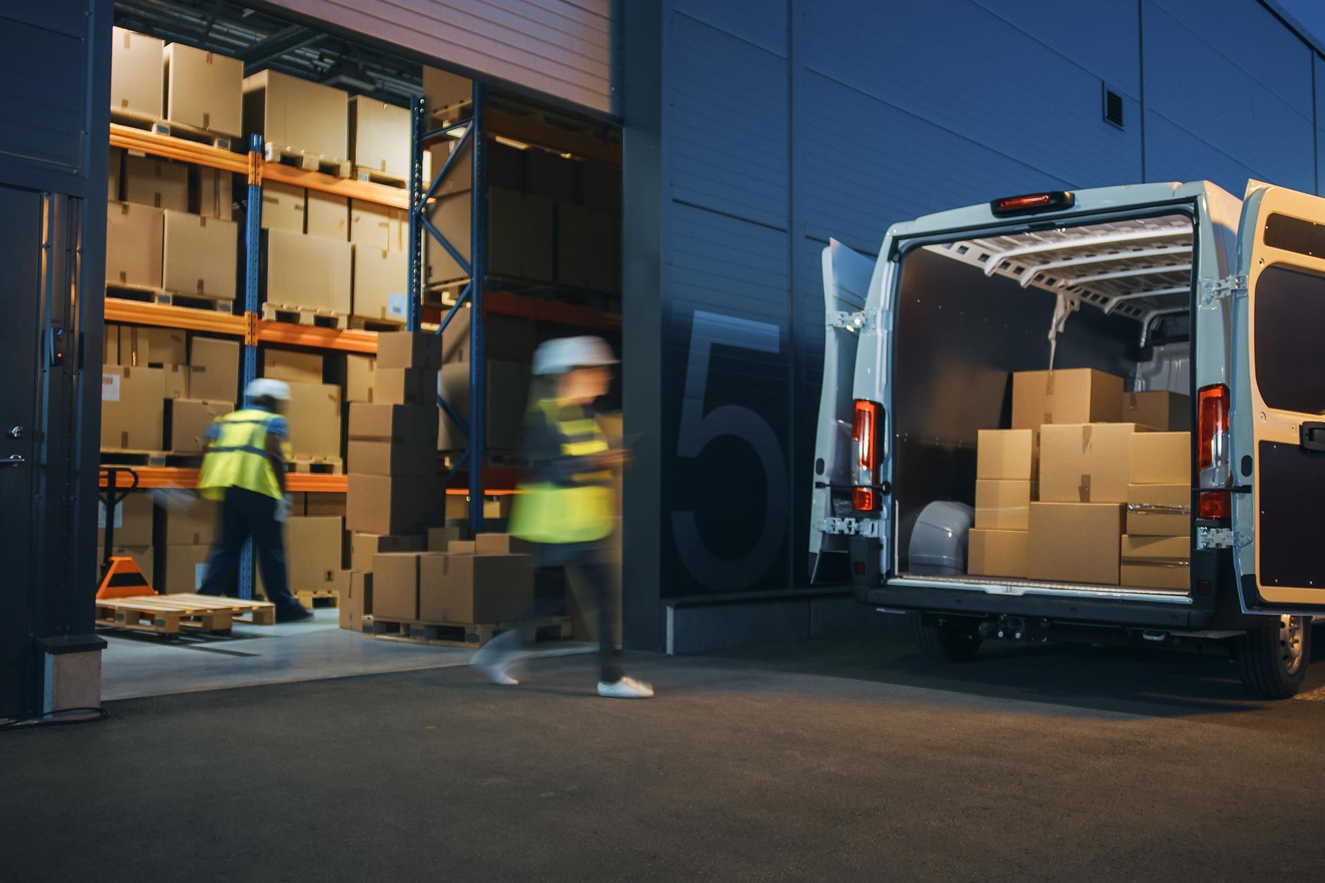 Delivery van loaded with boxes parked beside a warehouse loading area.