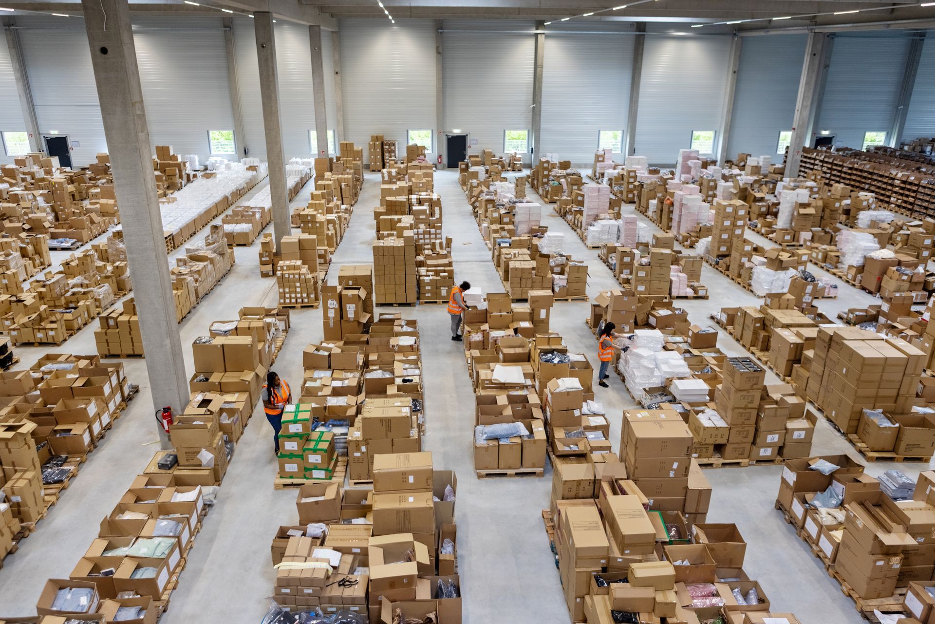 Large warehouse filled with stacks of cardboard boxes and pallets in long aisles