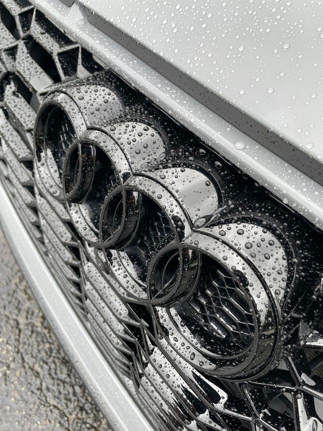 A man is cleaning the wheel of a black car with a sponge.