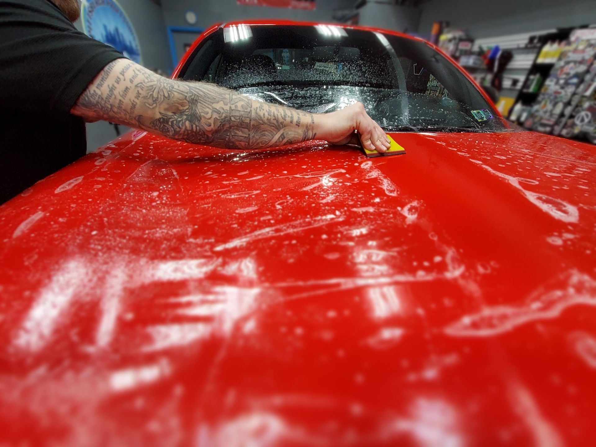 Two men are working on a red car in a garage.