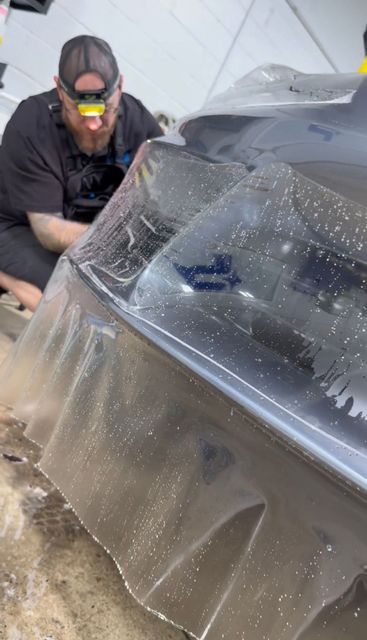 A man is wrapping a car with paint protection film