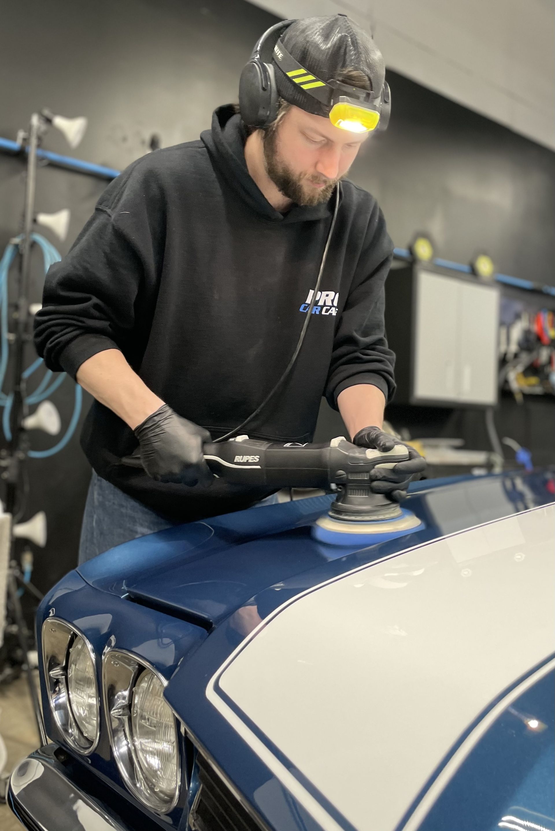 A man is cleaning the wheel of a black car with a sponge.