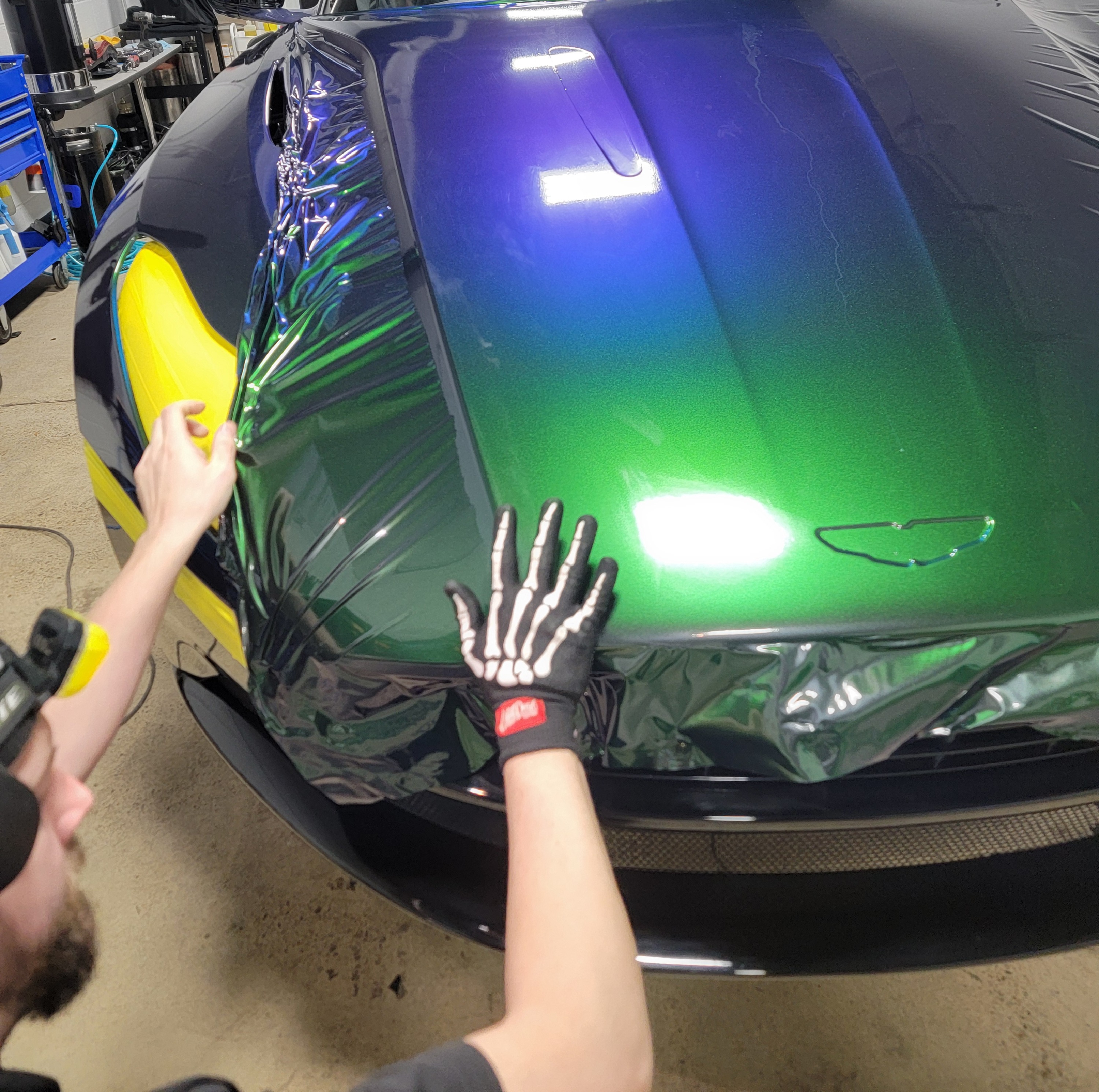 A man is cleaning the wheel of a black car with a sponge.