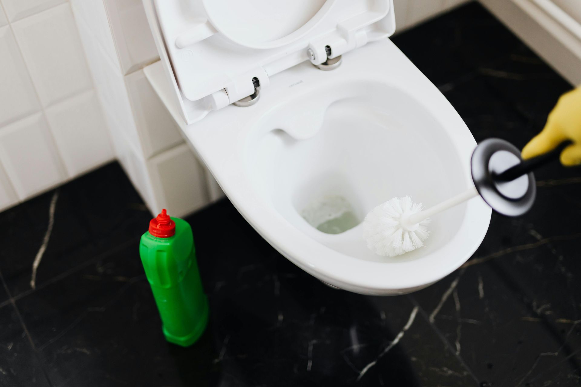 A person is cleaning a toilet with a toilet brush.