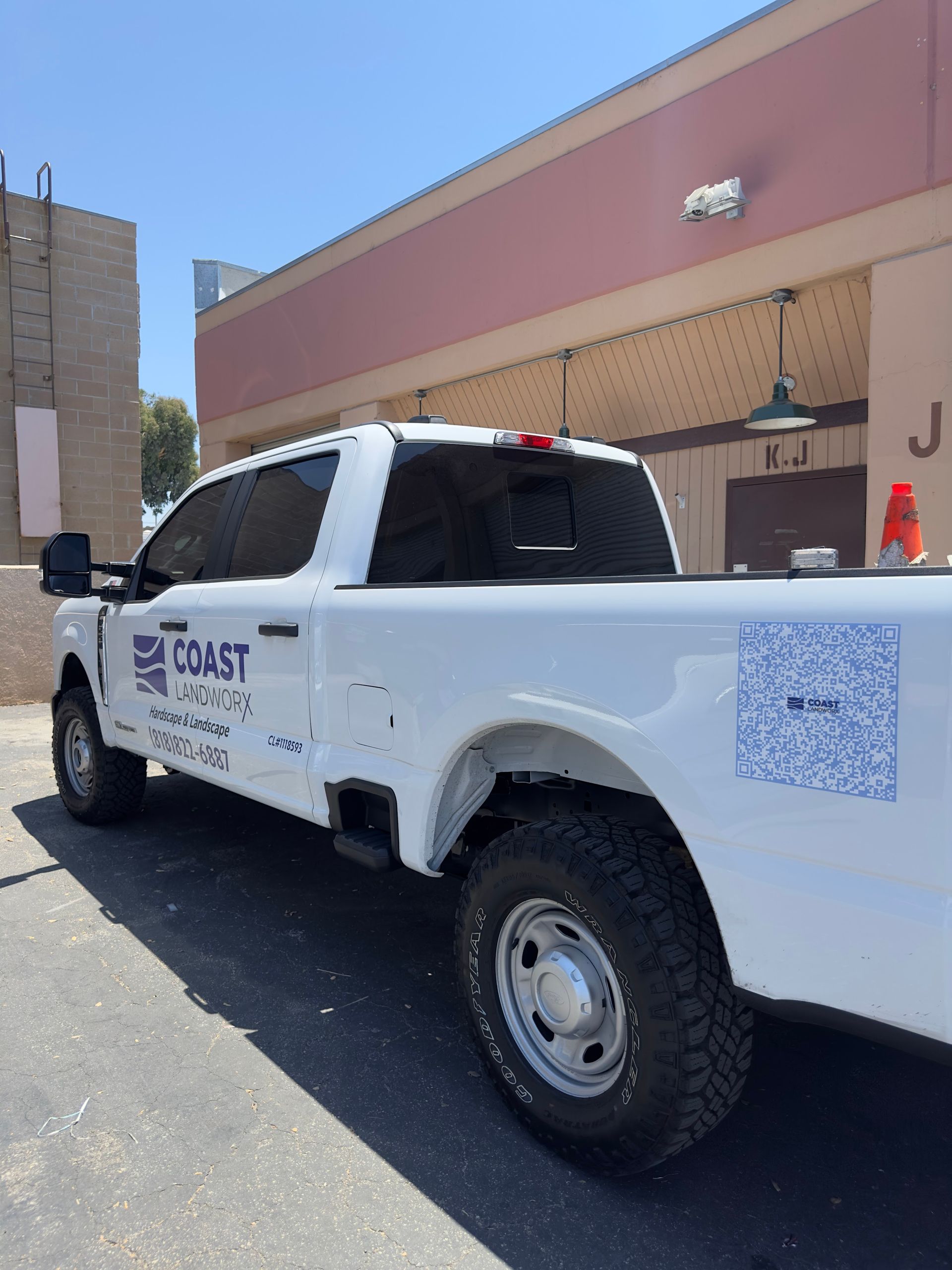 White Coast truck parked beside a tan building in bright sunlight.