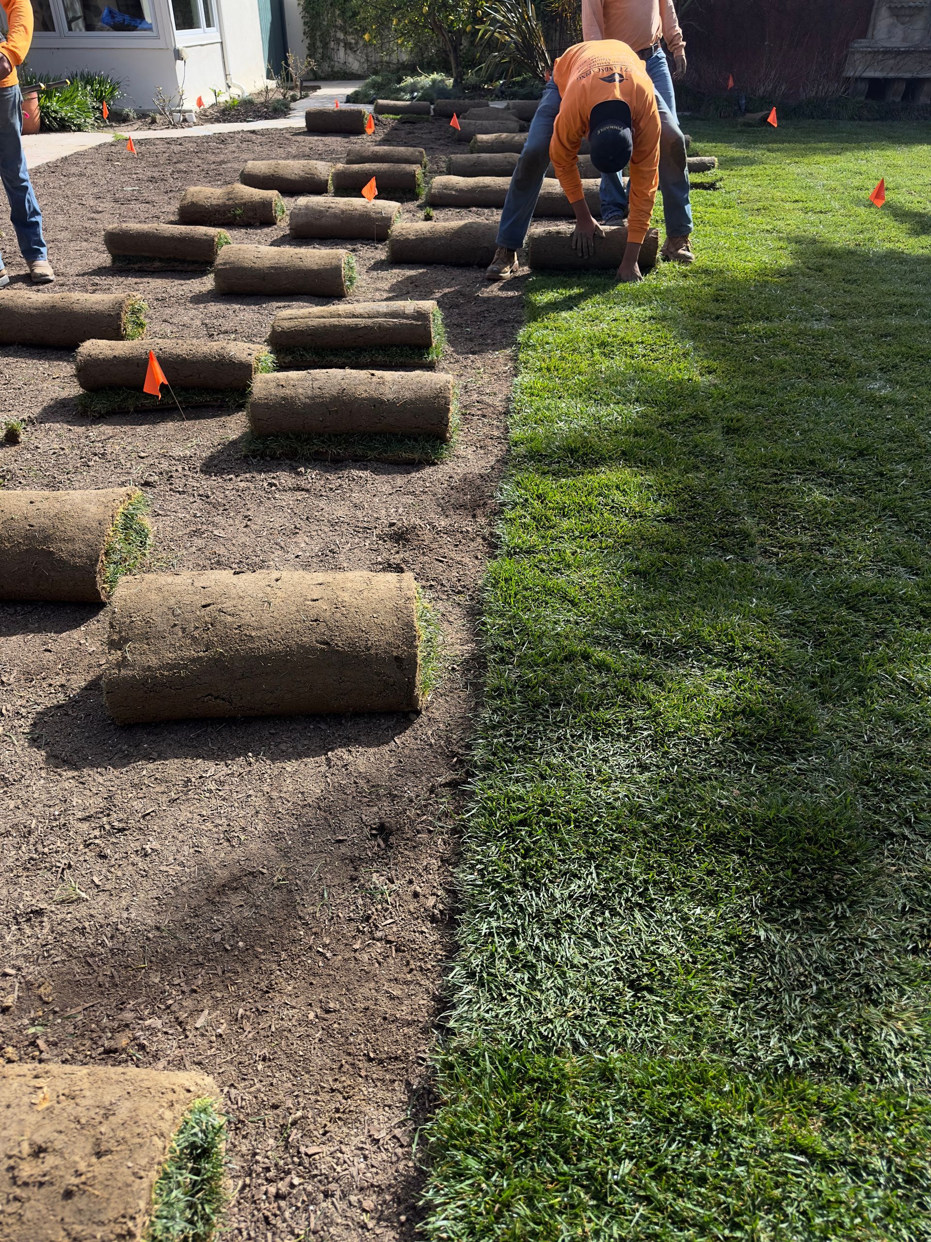 Person laying stepping stones in a gravel garden path beside green lawn