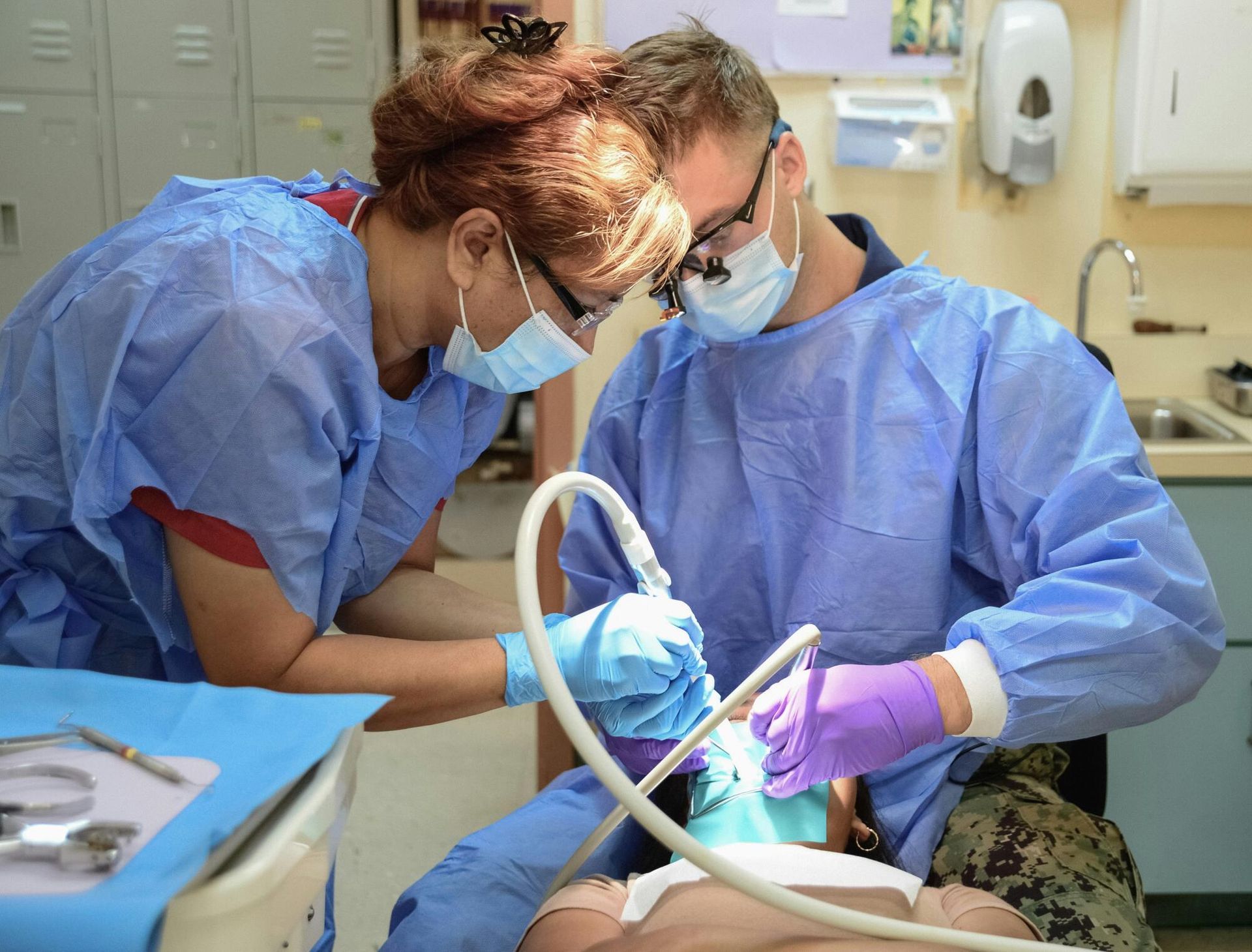Two dental professionals performing procedure on a patient in a clinic setting.