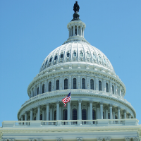 The United States Capitol Building with the American flag waving under a blue sky.