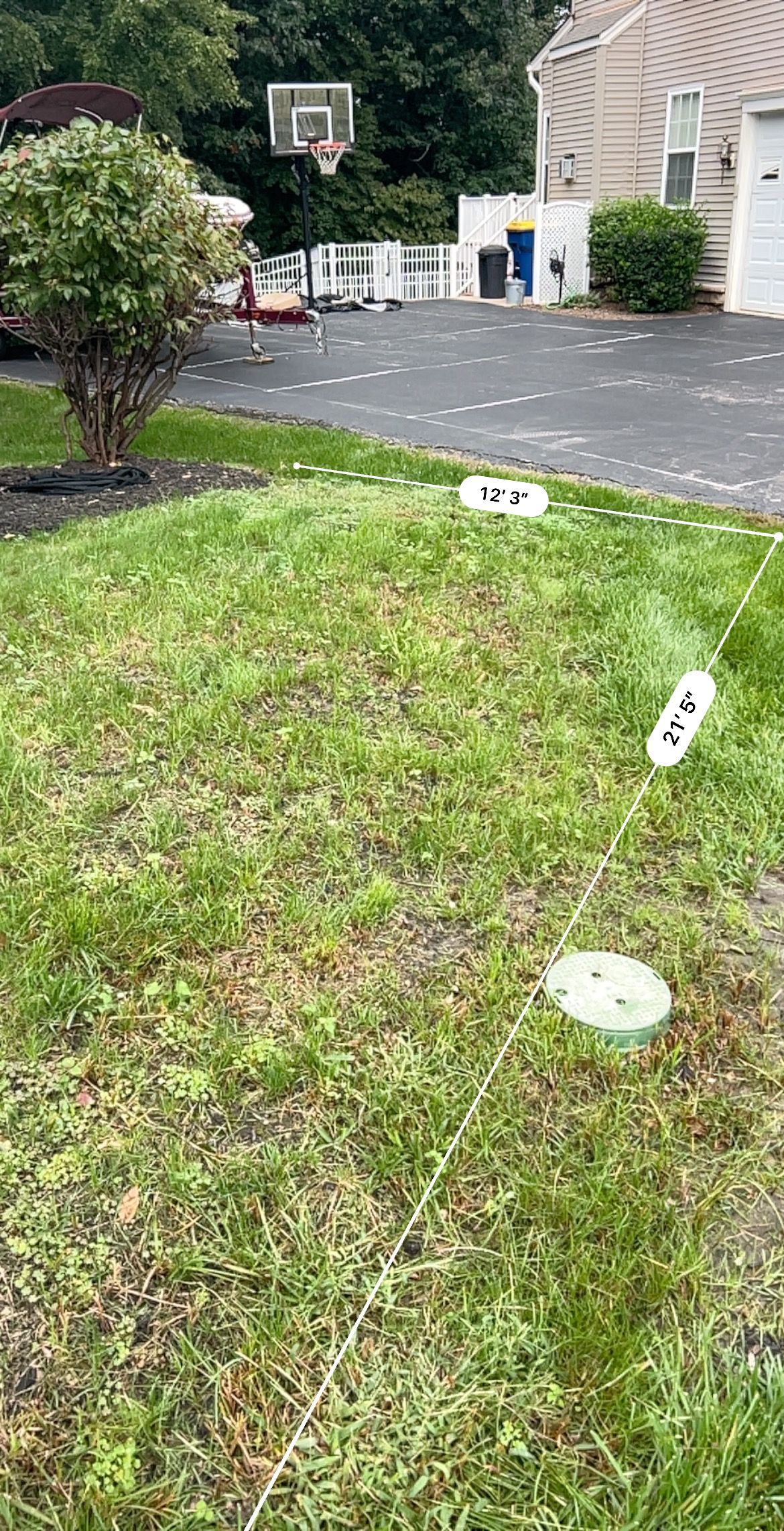 Front yard with green grass, white lawn lights, and a driveway beside a brick house.