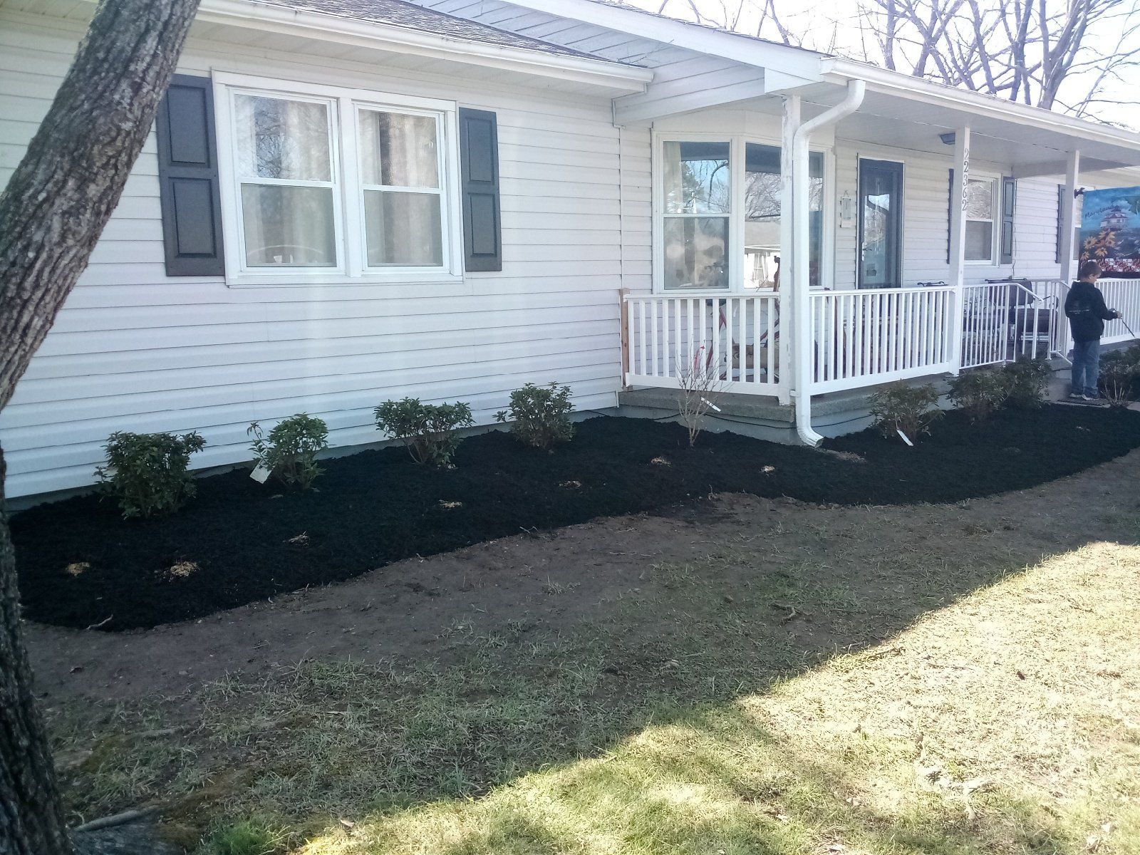 White house with porch and black mulch landscaping along the front yard.