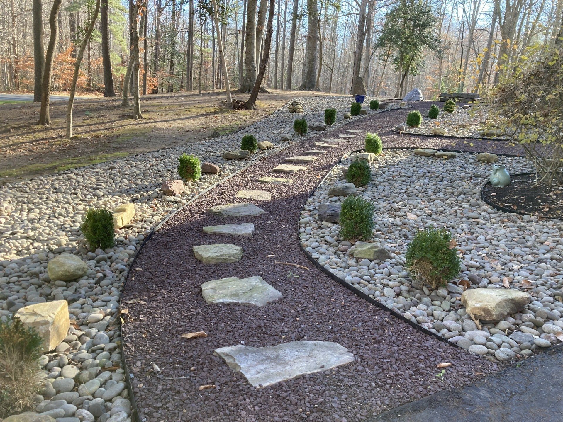 Curved gravel garden path with stepping stones and small shrubs in a wooded landscape