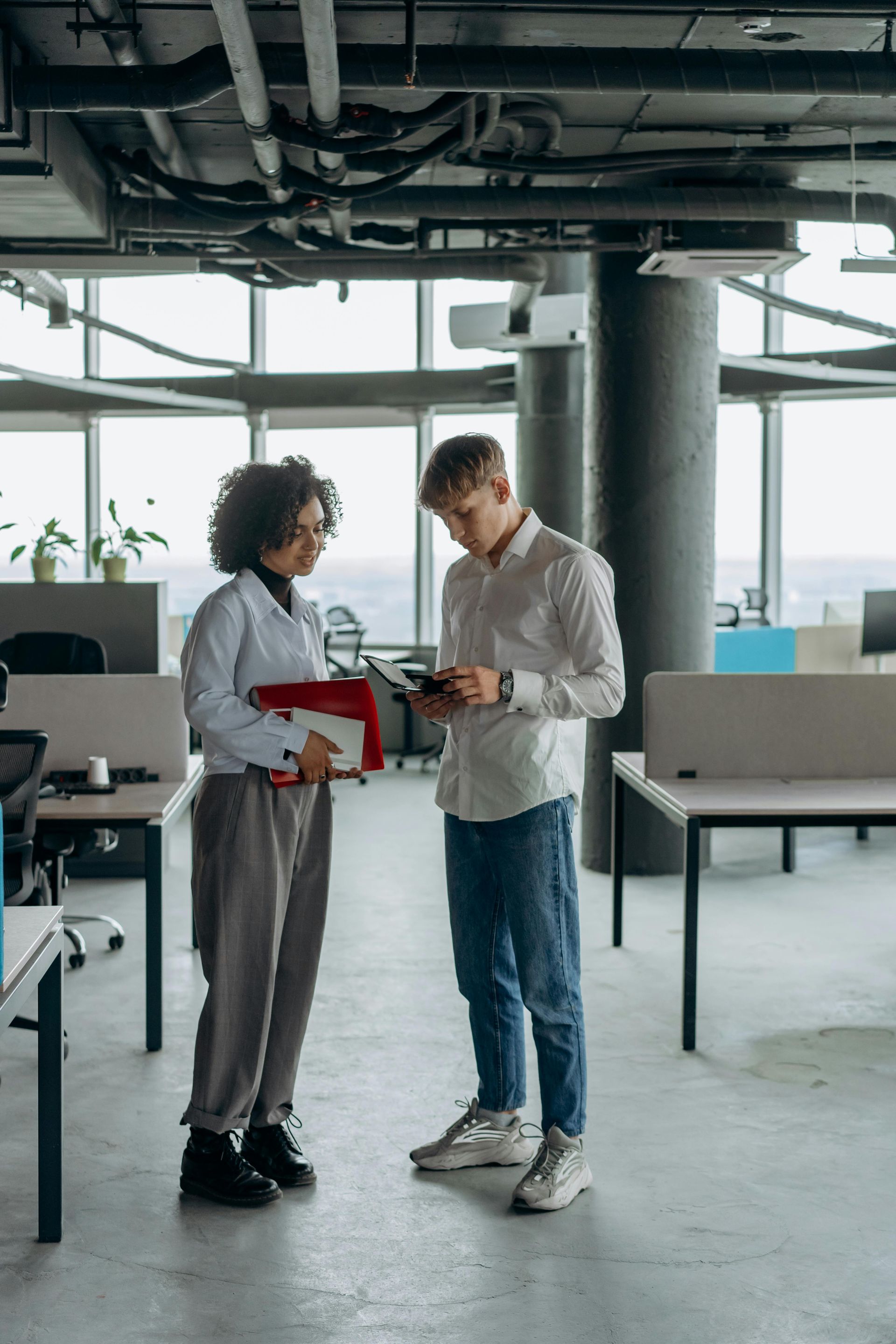 Two people discussing a tablet in an open office workspace