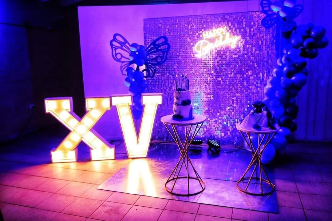 Una habitación con luces moradas y globos y una gran letra x en el suelo.