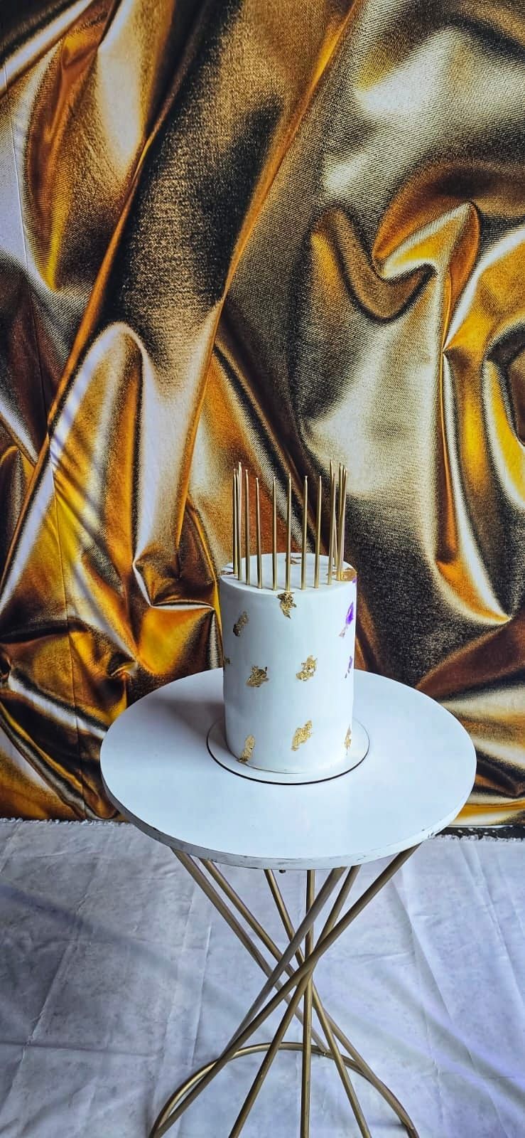 Un pastel con velas está sobre una mesa frente a un cuadro.