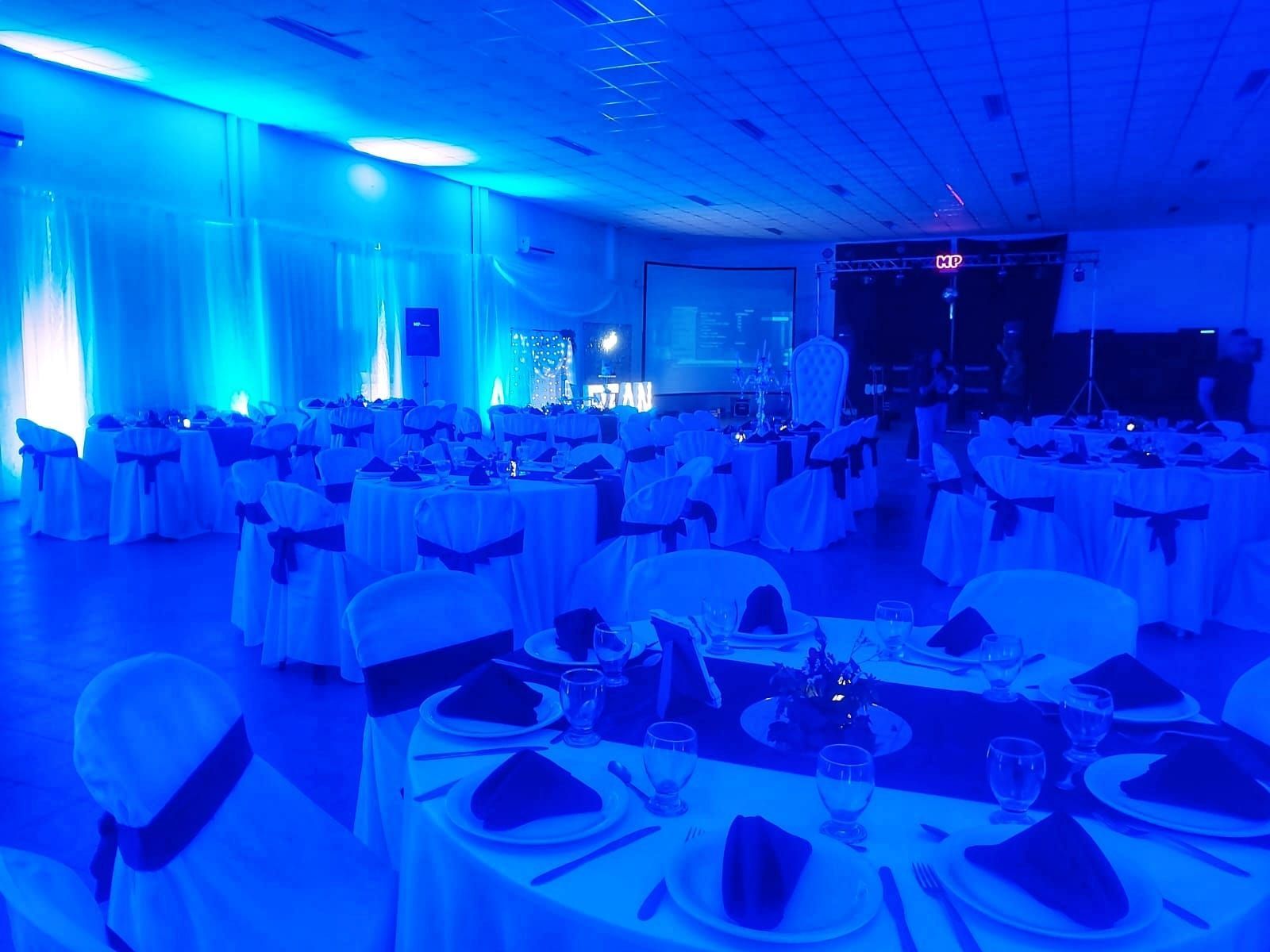 Una gran sala llena de mesas y sillas y luces azules.