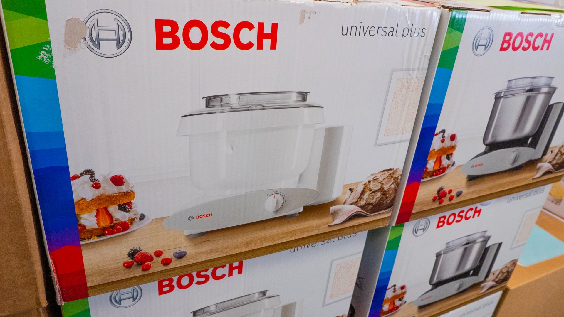 Boxes of Bosch Universal Plus kitchen mixers stacked on a shelf.