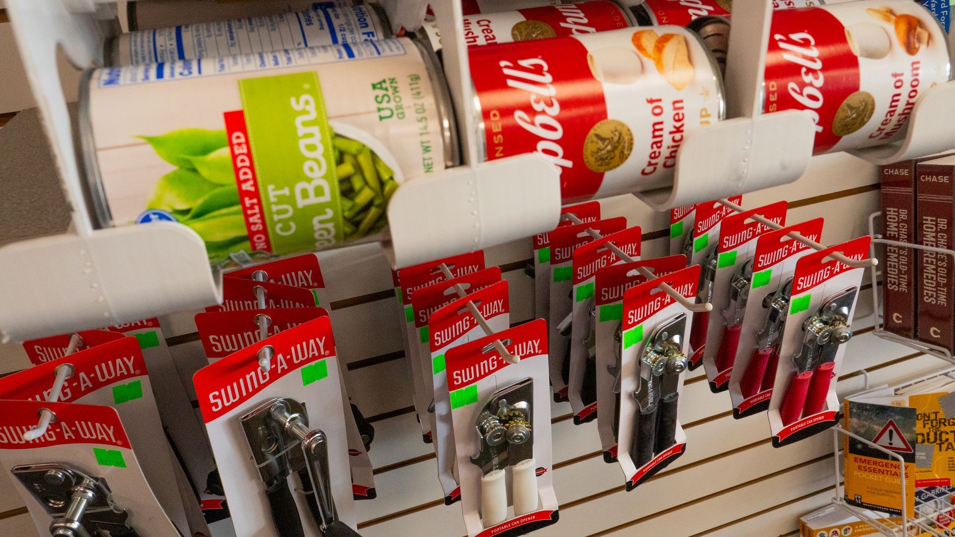 Canned goods on a shelf with can openers hanging below.  Green bean and cream of chicken soup cans are visible.