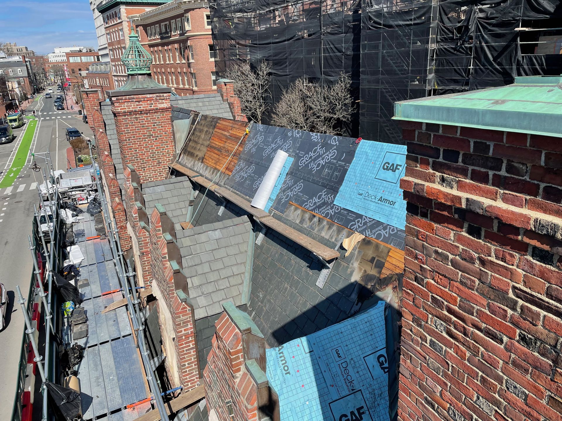 Historic roof restoration in progress with underlayment and chimney work at Harvard Lampoon