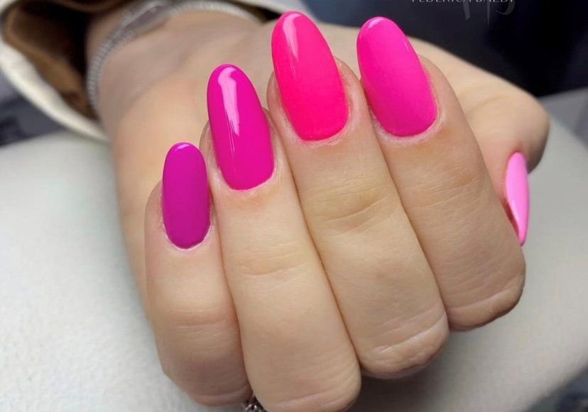 Mano con unghie laccate di rosa acceso e magenta.