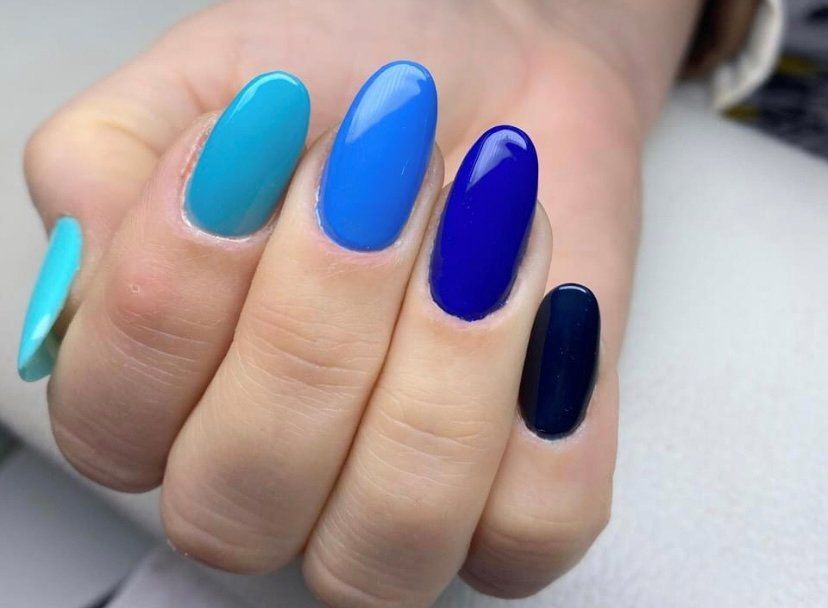 Mano con unghie lunghe dipinte con sfumature di blu e ciano.