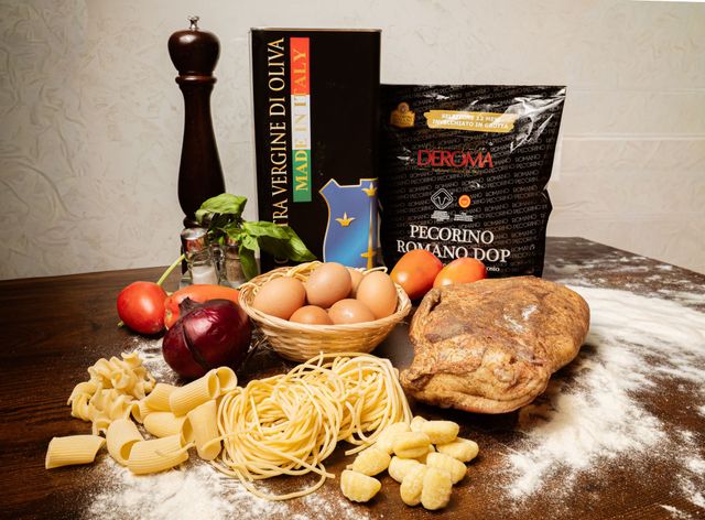 Ingredienti per la pasta con uova, pomodori, cipolla, farina, pepe, libro di ricette e pane su un tavolo