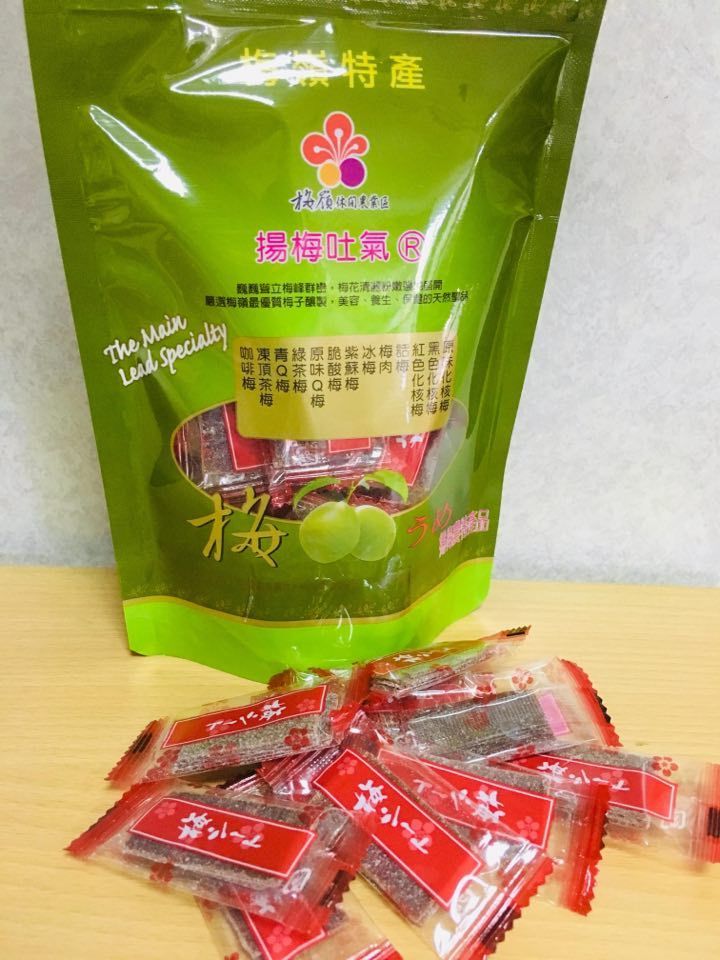 獨立包裝的梅子糖從一個半露在外的綠色袋子裡傾瀉而出,袋子放在木質表面上。