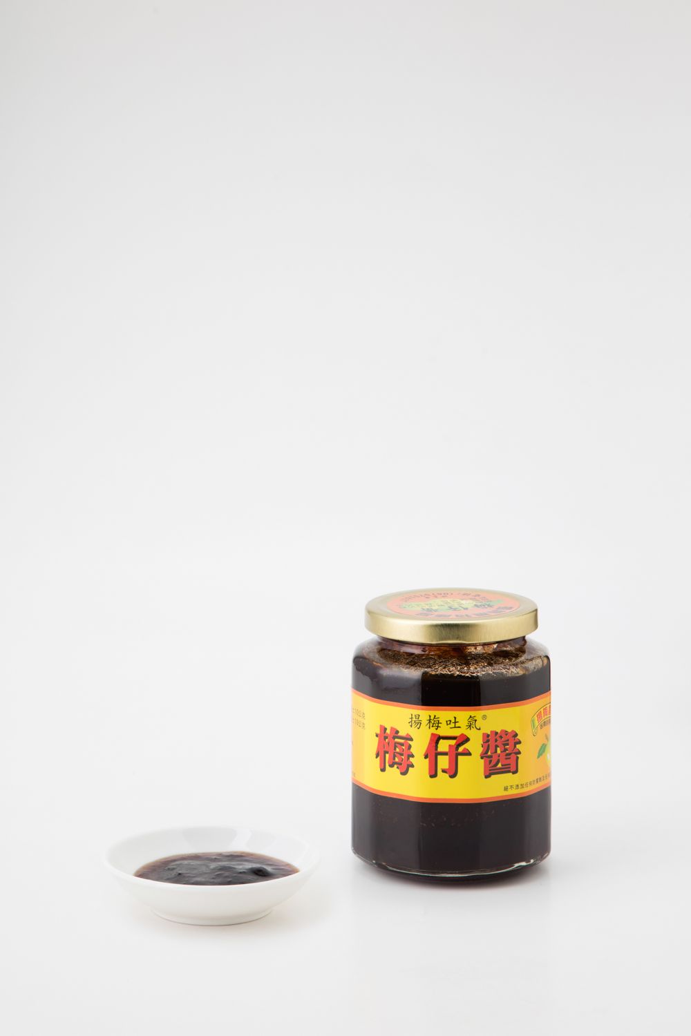 白色背景上的一罐深色李子醬和一小碟醬汁。