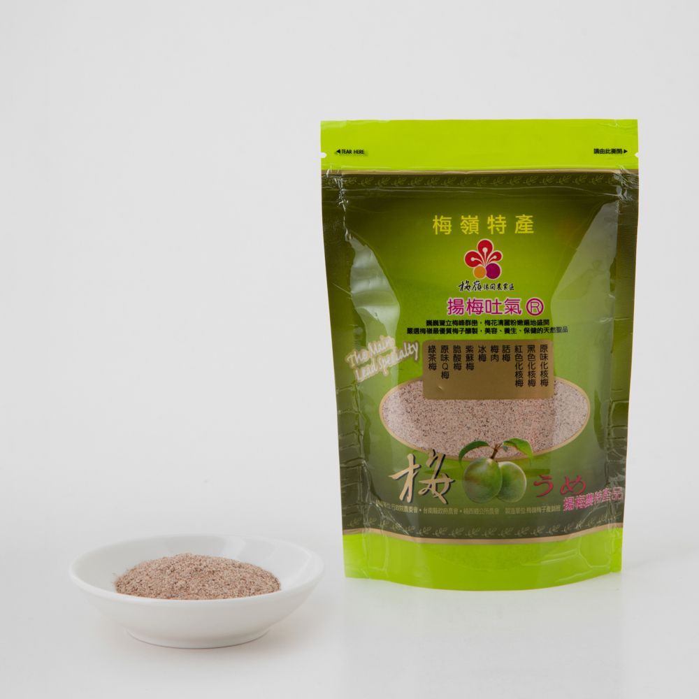 一袋梅子粉,旁邊放著一小碟粉末,置於白色表面。綠色包裝。