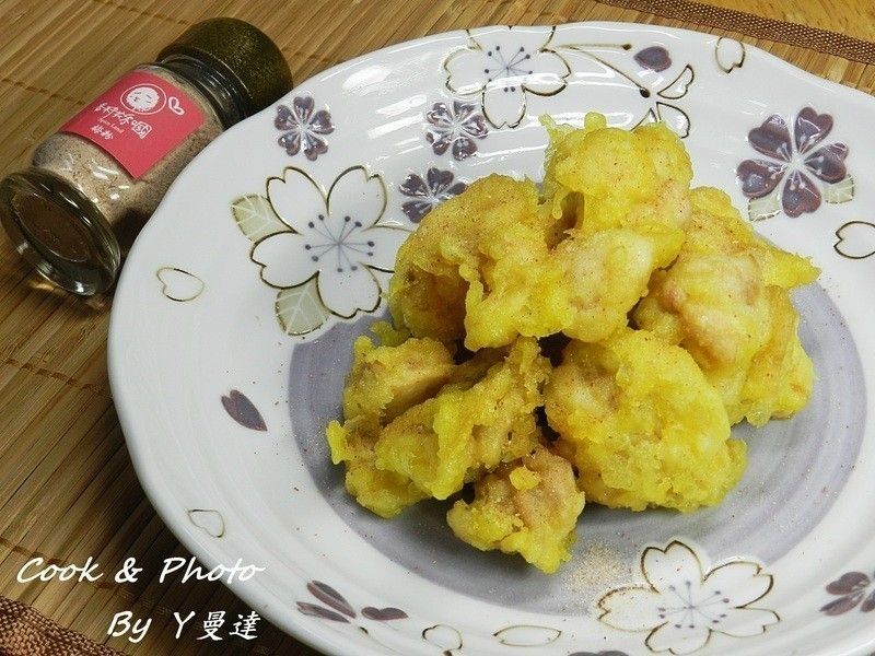金黃酥脆的炸物盛放在精美的盤子裡，背景中可以看到一個香料罐。