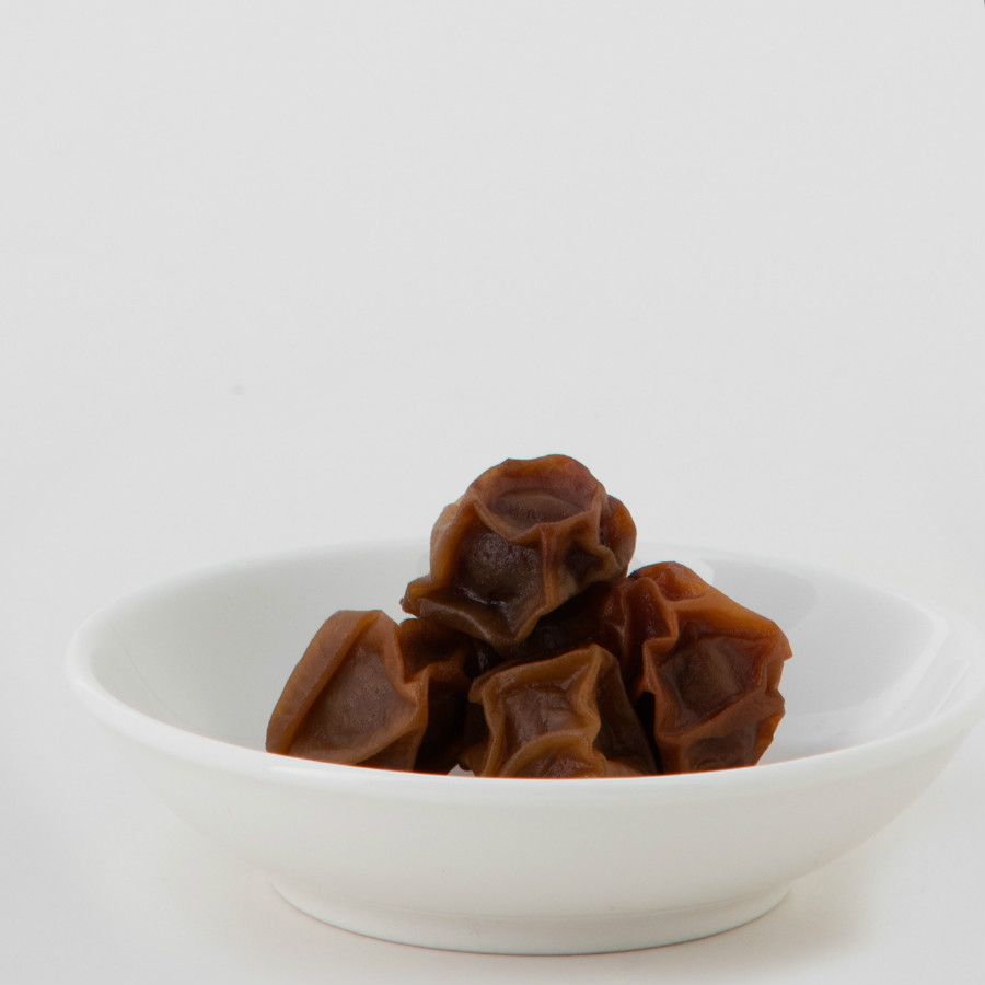 白色背景上的一袋乾梅子和一小碟乾梅子。
