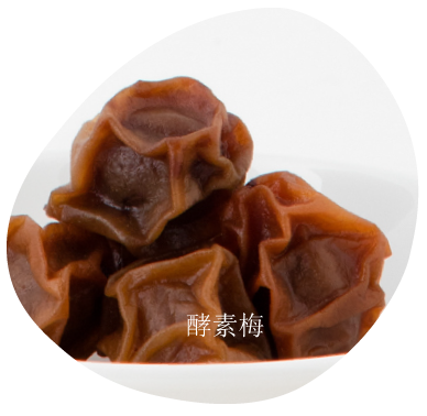 深棕色的蜜餞李子（酸梅）堆放在白色盤子上。