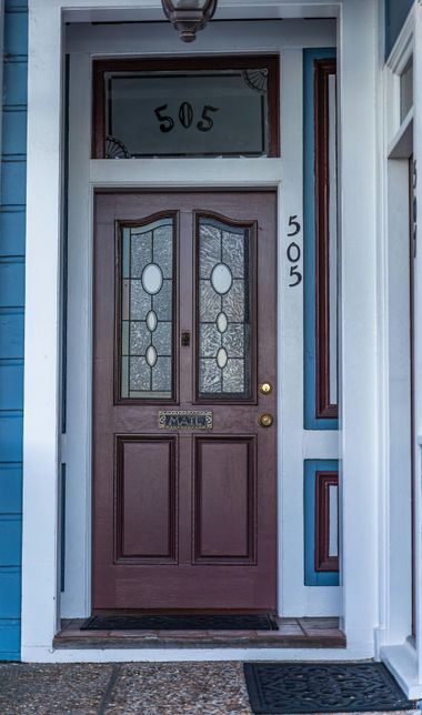 A wooden front door with stained-glass panels and a transom window, both labeled with the house number 505.
