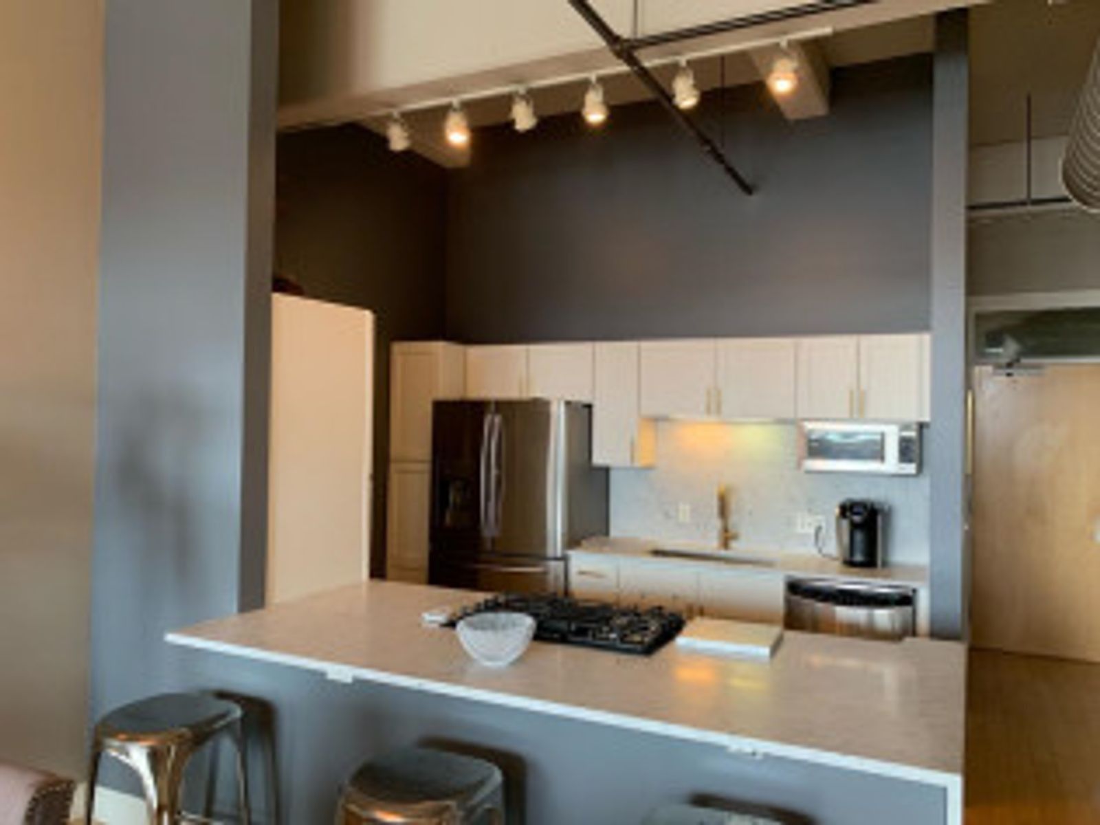 Modern kitchen with white cabinets, stainless steel appliances, and a gray accent wall.