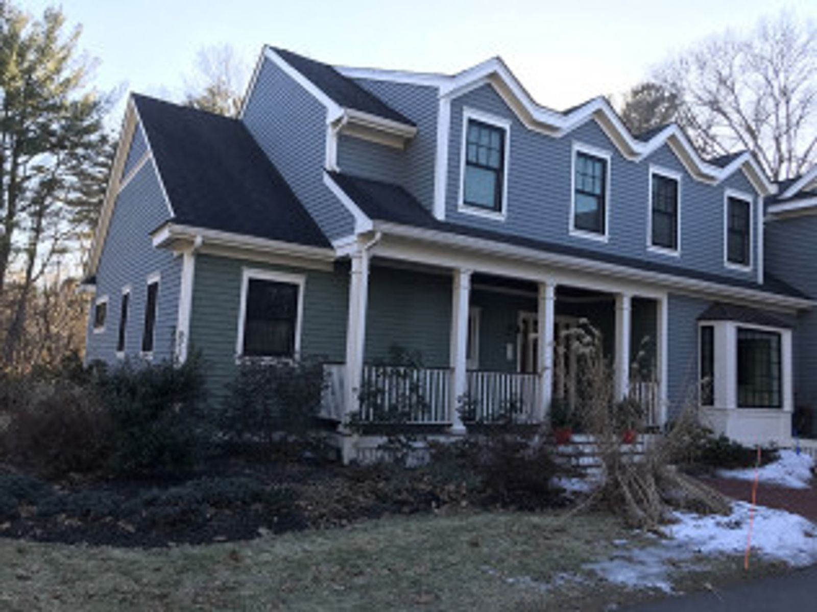 Two-story house with green and blue siding, white trim, and a porch, set in a winter landscape.