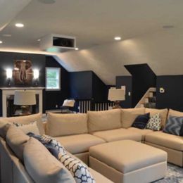 Cozy, finished basement living room with a large sectional sofa, fireplace, and projector screen.