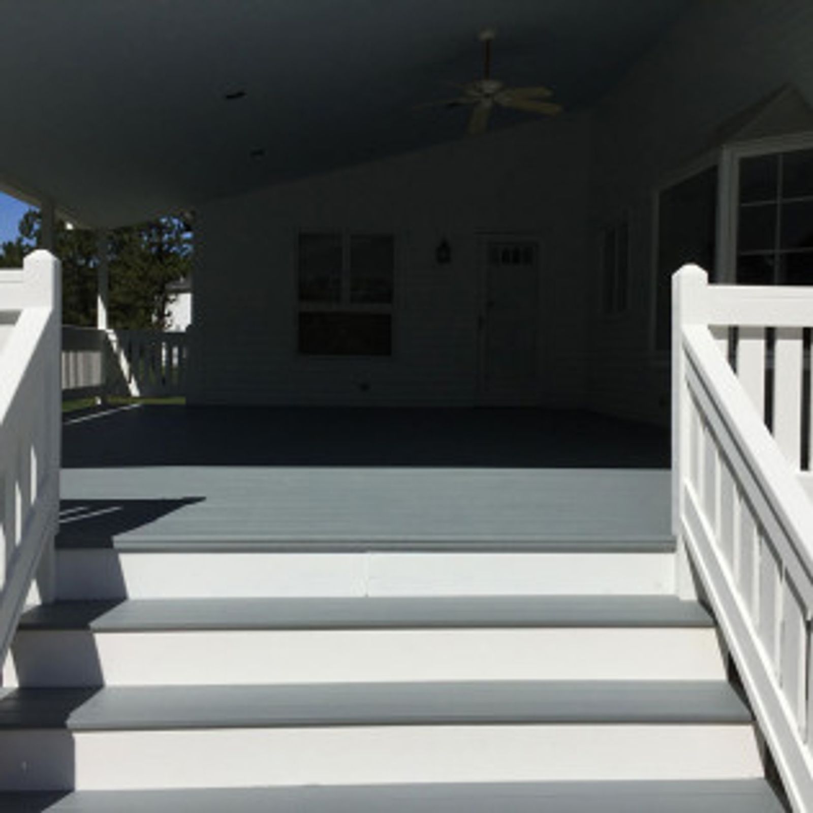 White deck steps leading to a covered gray deck, white railing.