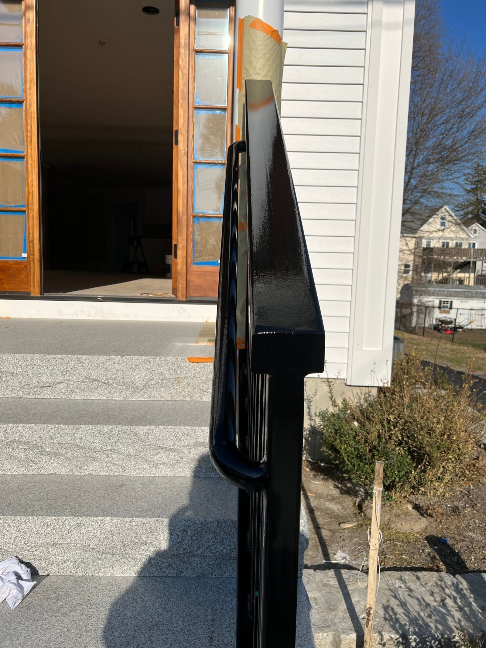 Black painted handrail on stone steps beside white building.