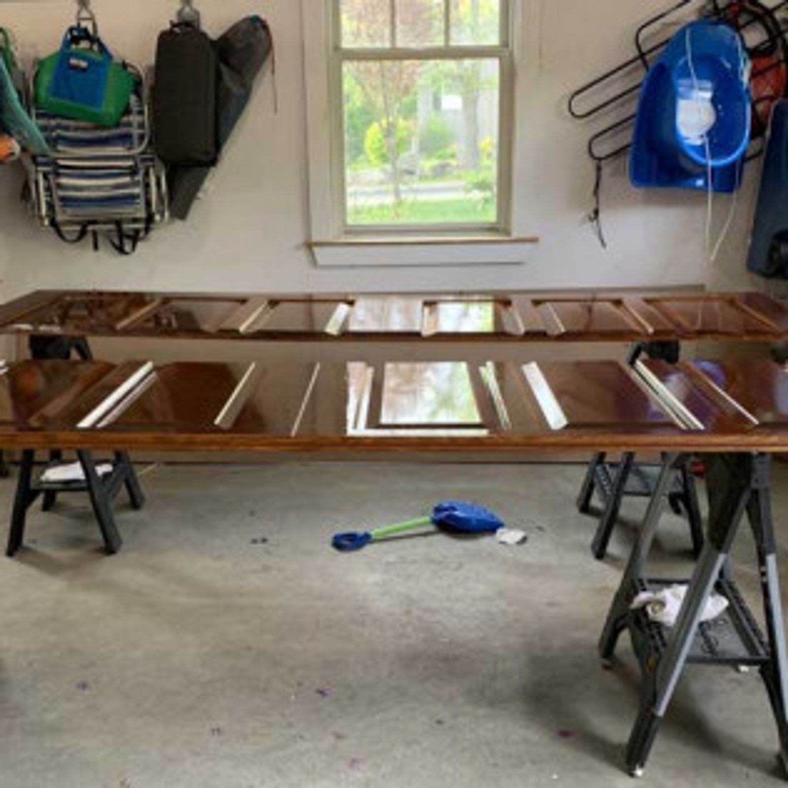 Long wooden doors on sawhorses, being refinished in a garage.