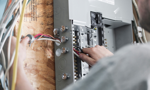 A man is working on an electrical box with a screwdriver.