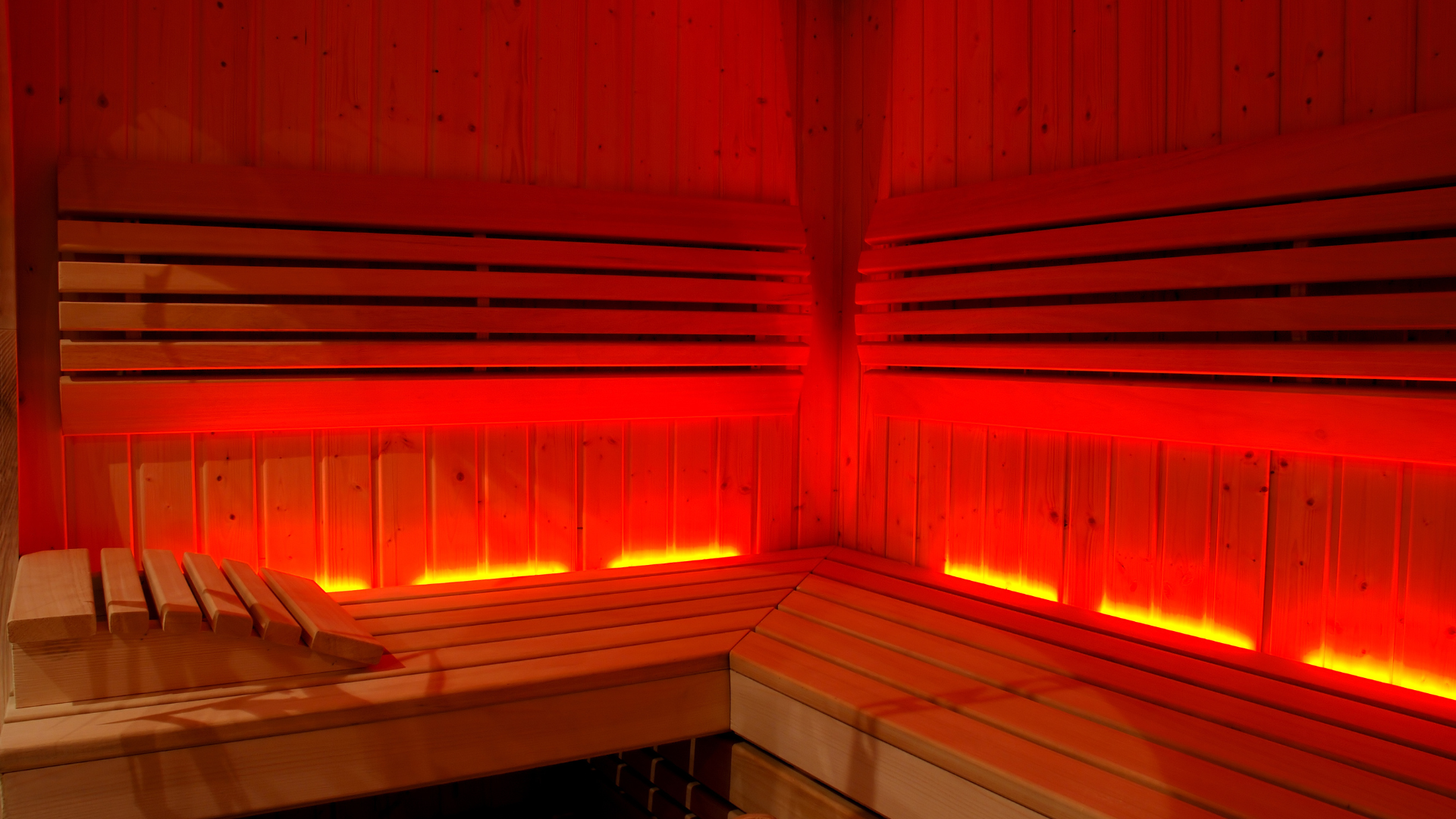 A wooden sauna with red lights on the walls and benches.