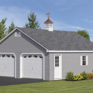 Gray two-car garage with white doors and cupola on a suburban home, beside a lawn and flowers