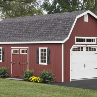 Red barn-style garage with white doors and trim, front view, beside a green lawn.
