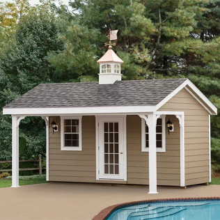 Small beige poolside shed with white trim, front porch, and cupola beside a swimming pool