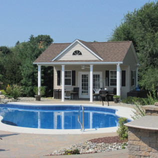 Backyard with a small blue swimming pool in front of a beige pool house with white columns