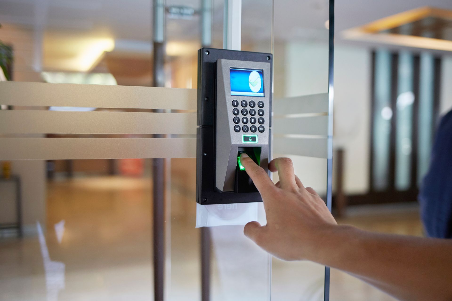 Person using an access control system fingerprint scanner to unlock a glass door