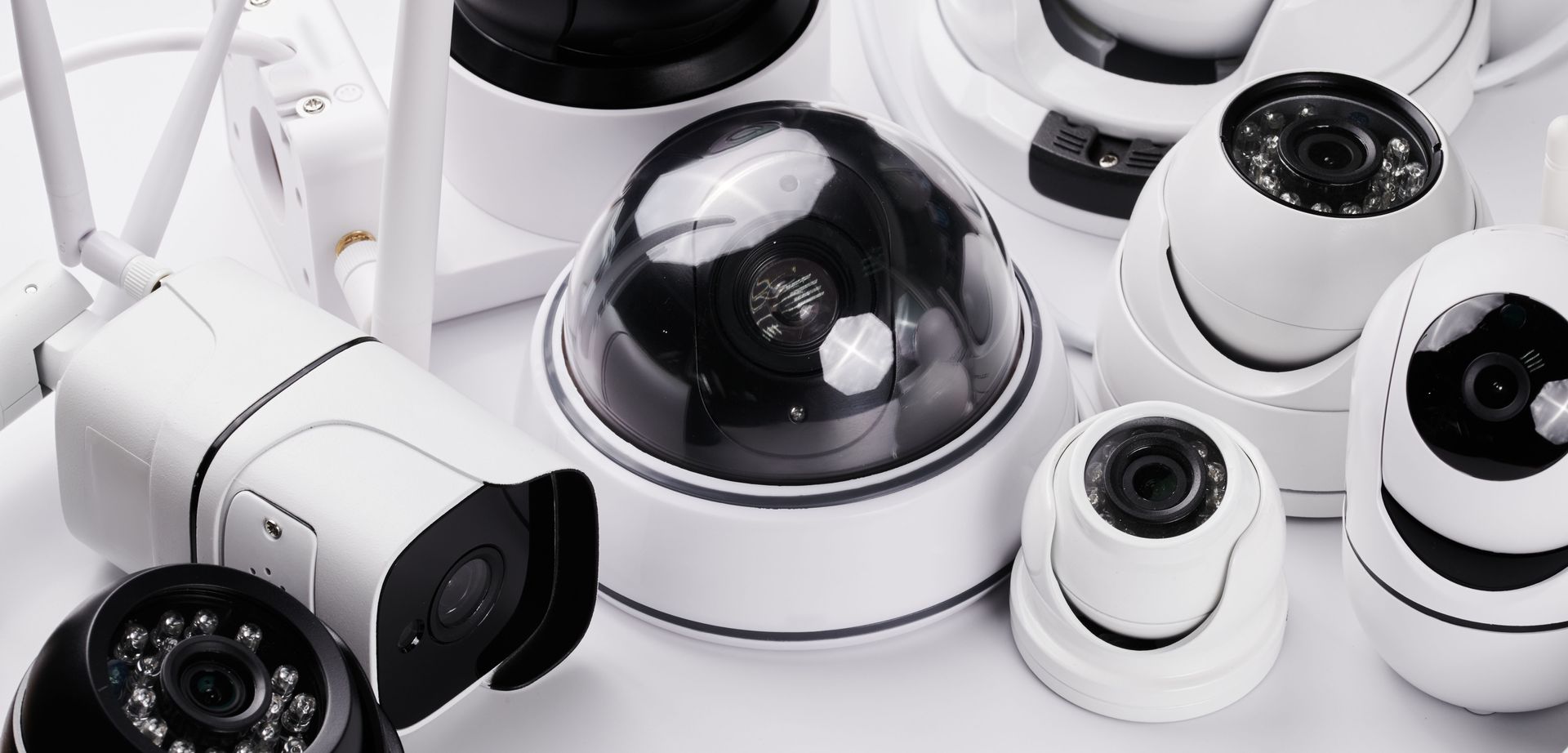 Assorted white dome and bullet security cameras used by a home security system installer.