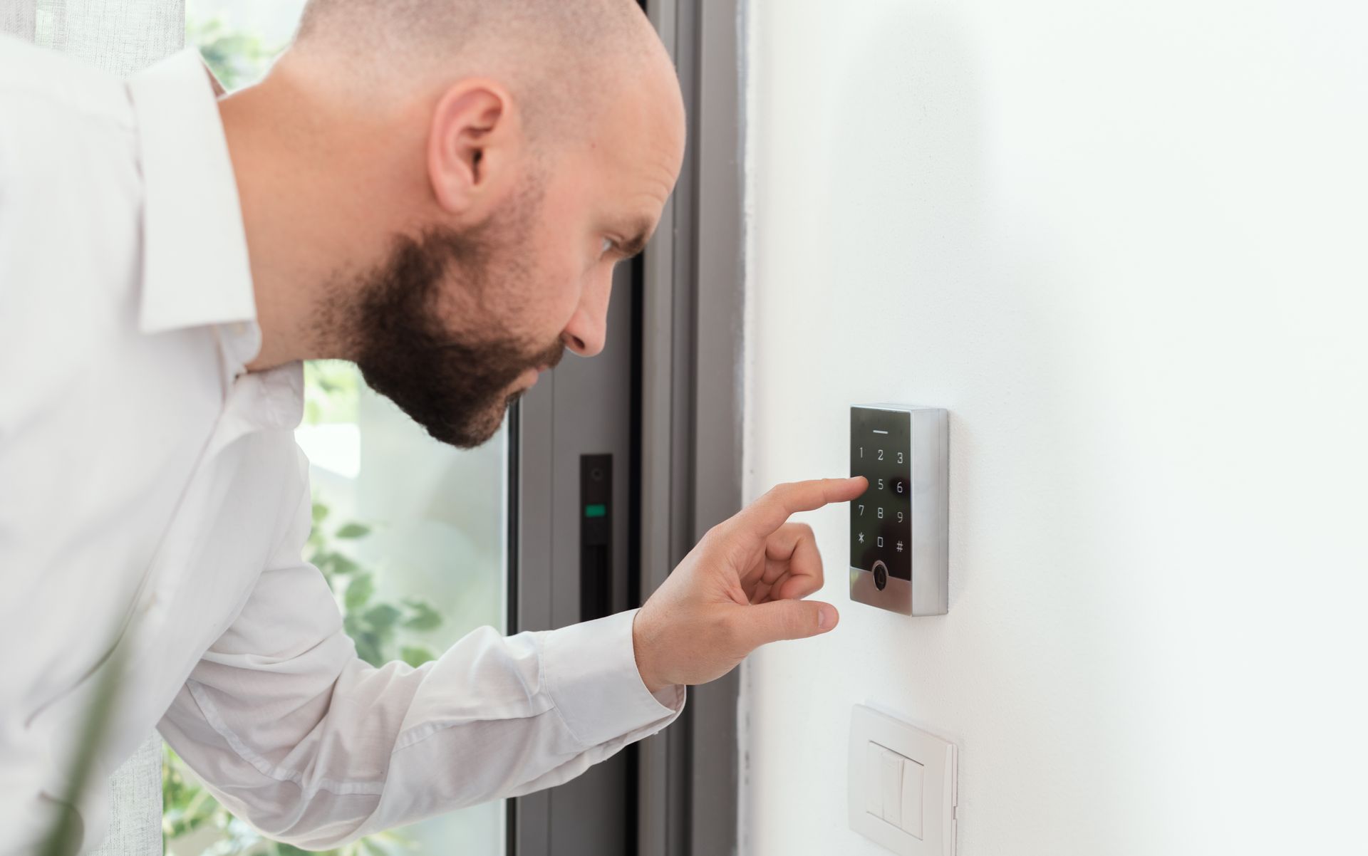 Man arming a wall-mounted security keypad installed by a residential security system installer.